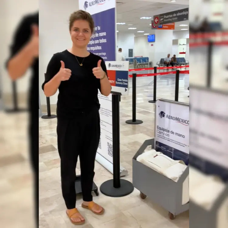 Person giving a thumbs-up in an airport with AeroMexico branding.