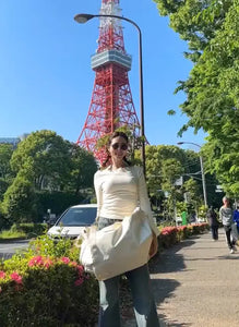 Person in a white dress standing in front of Tokyo Tower with greenery around