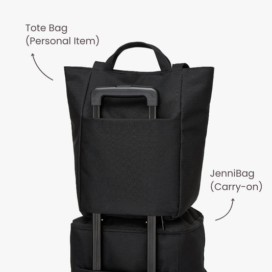 Black tote bag and carry-on bag stacked on a white background.