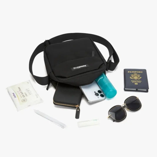 Black crossbody bag with travel items including a phone, passport, and sunglasses on a white background.