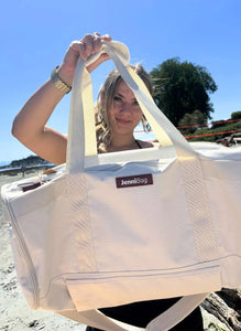 Person holding a beige JenniBags bag on a beach