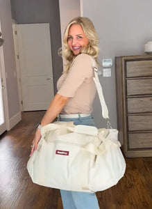 Woman holding a large white bag with a visible brand logo in a room.