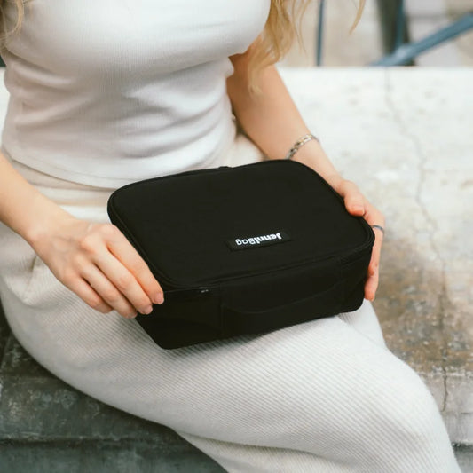 Person holding a black travel case on a bench.