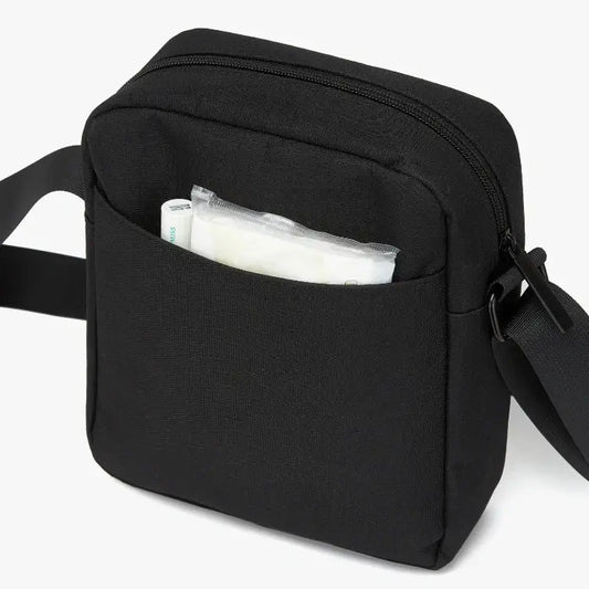 Black crossbody bag with a pocket open, showing a white bag inside on a white background.