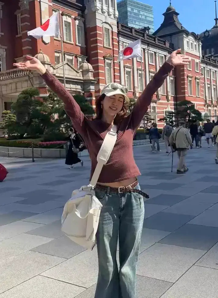 Person holding Japanese flags in a city square with a large building in the background