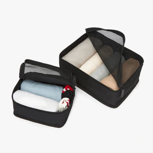 Black packing cubes with folded clothes on a white background