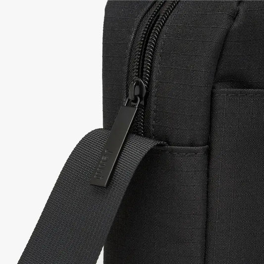 Close-up of a black backpack's zipper and shoulder strap.