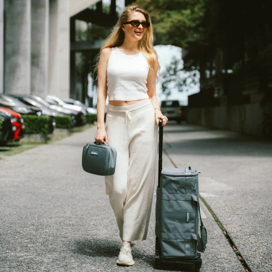 Woman walking with a suitcase and green bag in an urban setting