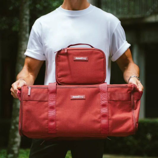 Person holding two red bags outdoors