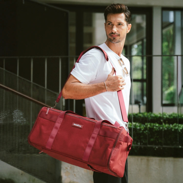 Man holding a red duffel bag outdoors