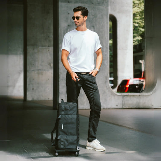 Man pulling a black suitcase in an urban setting