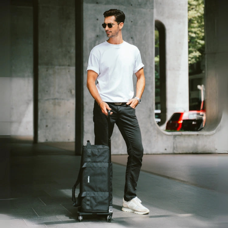 Man pulling a black suitcase in an urban setting