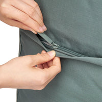 Close-up of hands zipping a green garment.