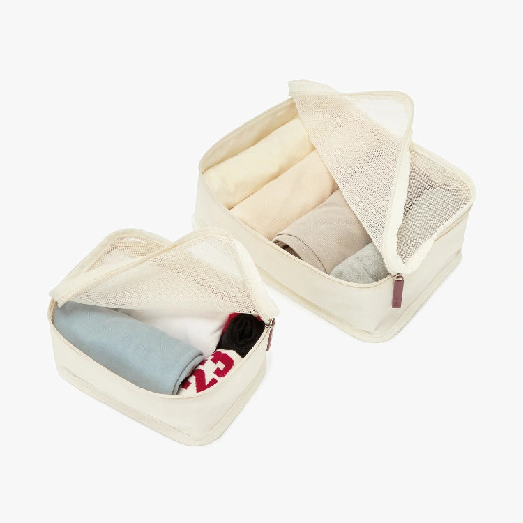 Beige fabric storage cubes with clothes on a white background