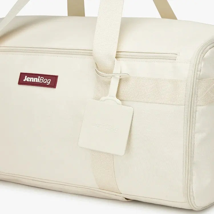 Beige duffel bag with a tag and handle detail.