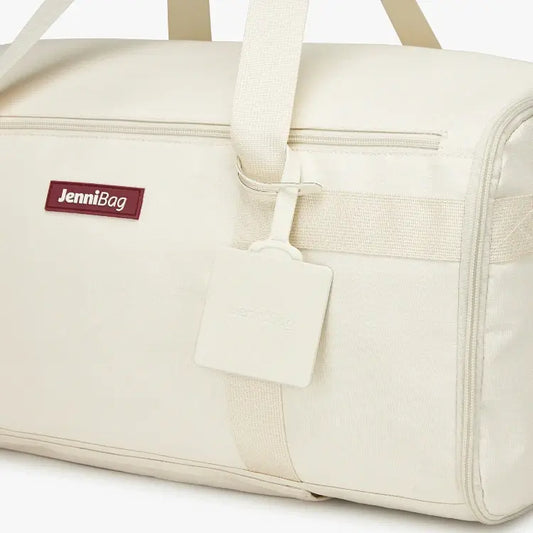 Beige duffel bag with a tag and handle detail.