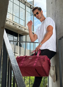 Man holding a red bag outdoors near a building