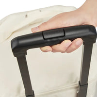 Hand holding a black suitcase handle with a visible brand logo against a neutral background