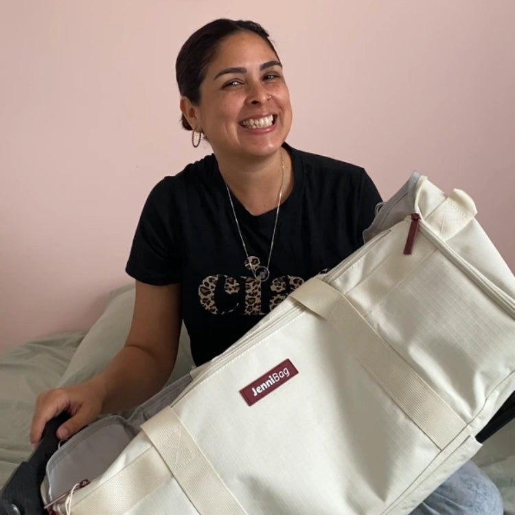 Person holding a white bag with a brand logo against a pink wall