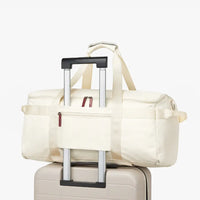 White duffel bag with wheels attached to a suitcase on a white background
