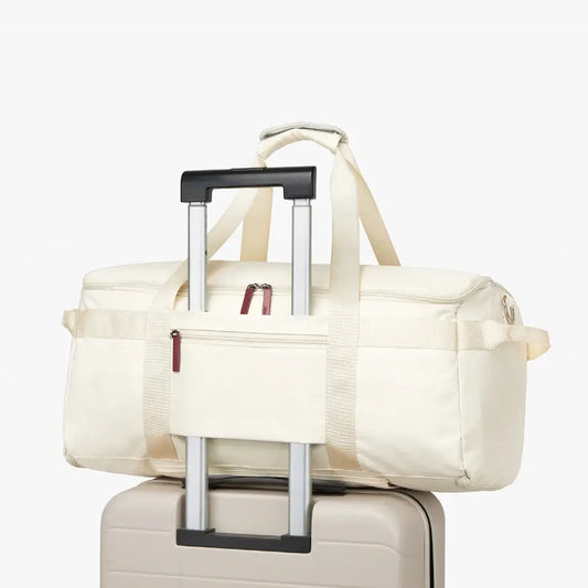 White duffel bag with wheels attached to a suitcase on a white background