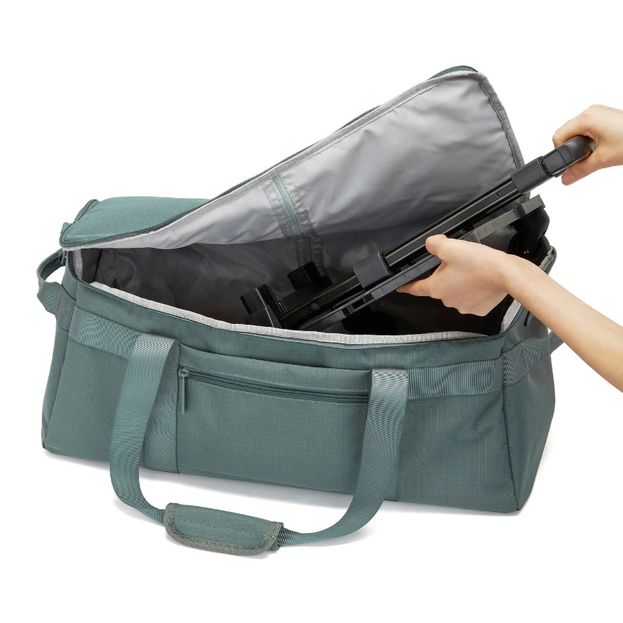 Green duffel bag with a suitcase being placed inside on a white background