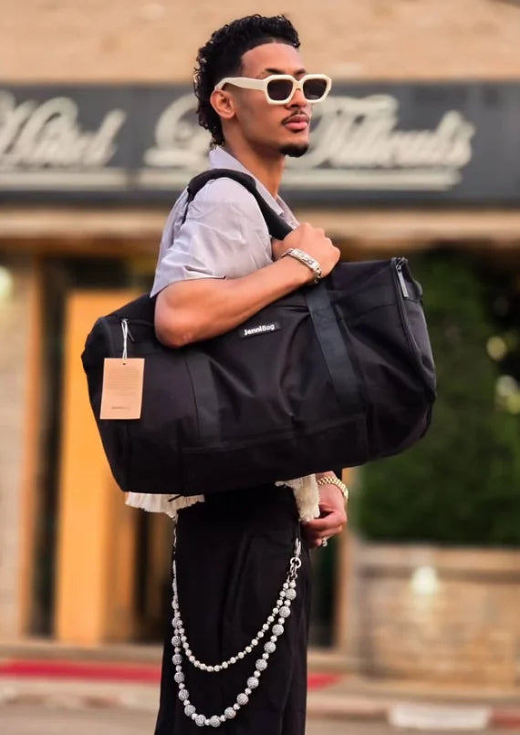 Male traveler carrying a black JenniBag outdoors