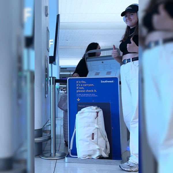 Cream JenniBag standing in front of a Southwest Airlines “If it fits, it’s a carryon” sizer