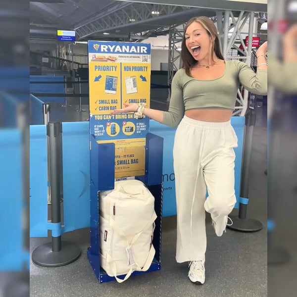 Traveler beside a Ryanair Priority and Non-Priority bag sizer with a cream JenniBag inside