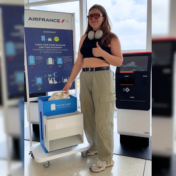 Traveler placing a cream JenniBag into Air France’s blue hand-baggage sizer
