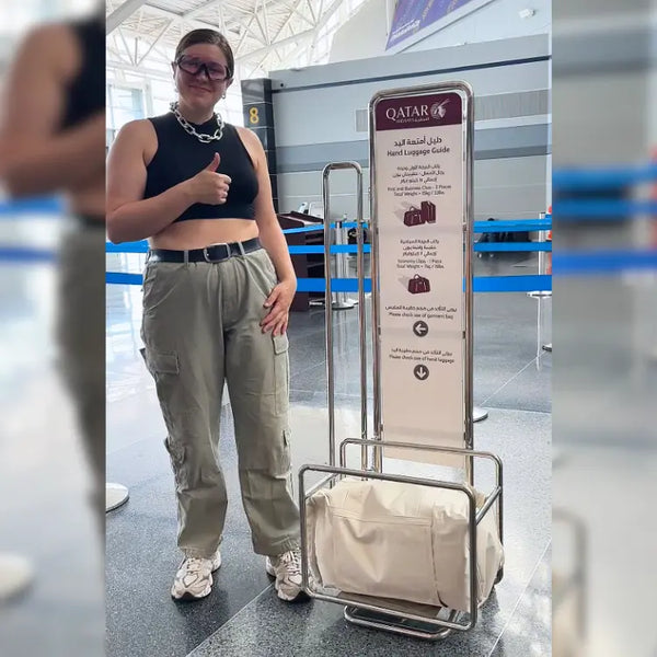 Traveler beside a Qatar Airways hand-baggage sizer with a cream JenniBag inside