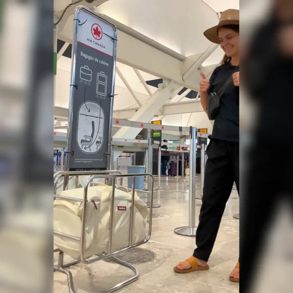 Traveler giving a thumbs-up beside an Air Canada cabin-baggage sizer with a cream JenniBag inside