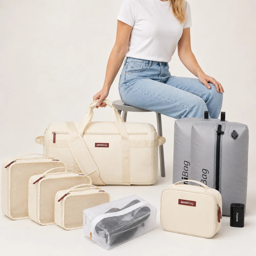 Woman seated beside the complete beige JenniBag Travel Bundle: JenniBag, Vacuum Kit, packing cubes, cosmetic bag and shoe bag