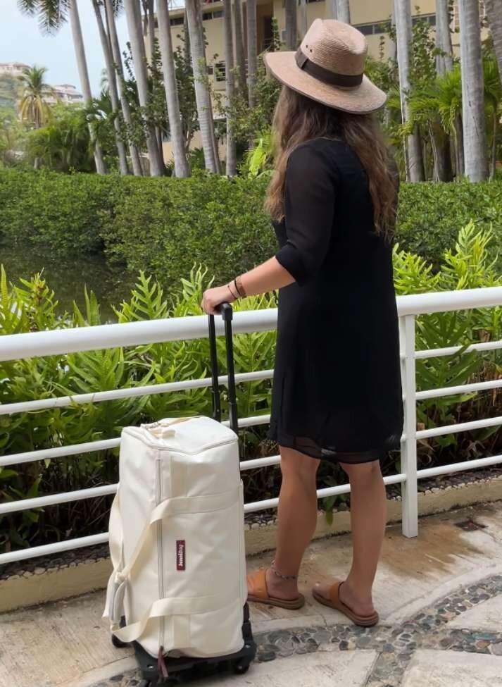 Customer pulling a beige JenniBag Roller Edition at a resort