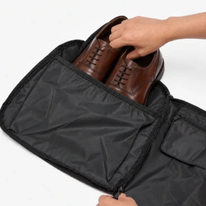 Brown dress shoes being placed into a dedicated shoe compartment.